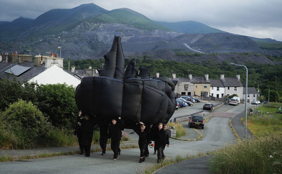 A group of men carrying inflatable sculpture up a hill